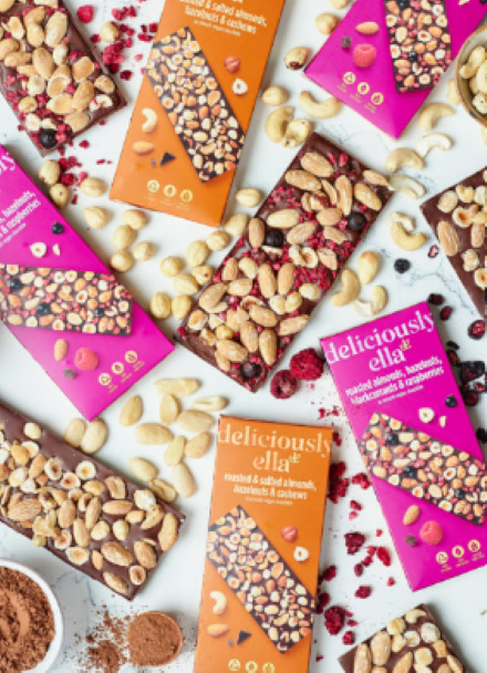 Selection of deliciously ella chocolate bars surrounding with nuts and dried fruit